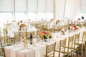Elegant wedding reception space with gold chiavari chairs and long tables, with floral centerpieces. Flowers by Eastern Floral.