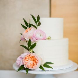 Two-tiered white wedding cake accented with pink and peach peonies. Flowers by Eastern Floral.